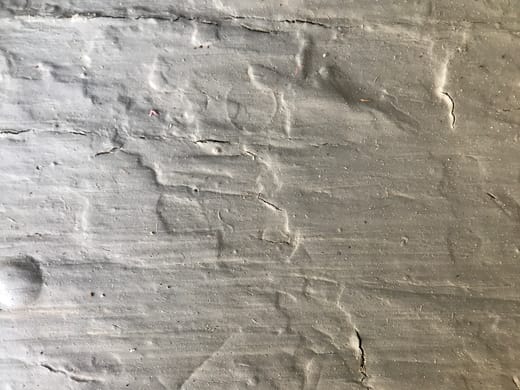 Rough textured concrete wall surface showing hairline cracks that can be sealed with crack injection