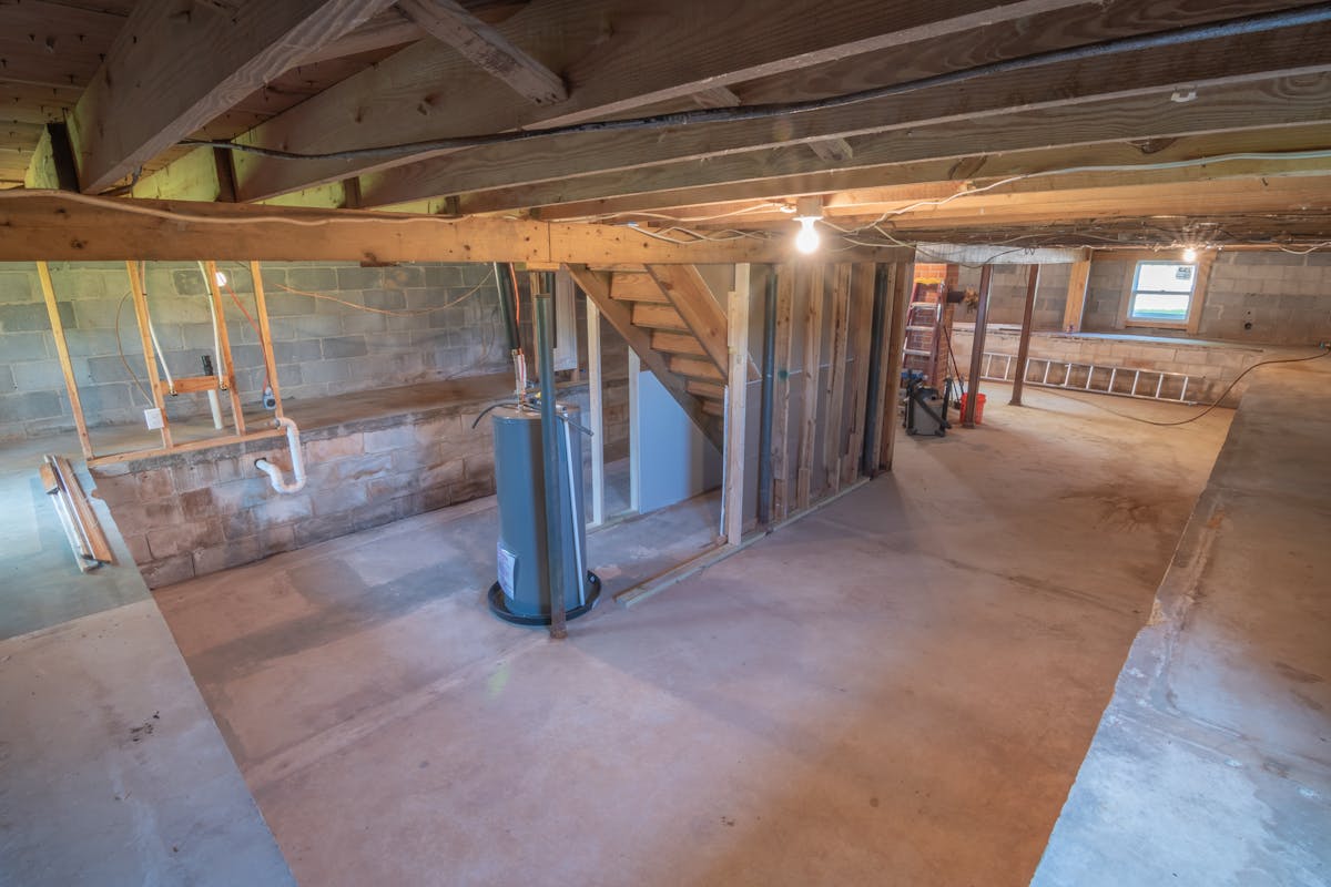 Empty Hoboken basement with exposed plumbing, ready for waterproofing